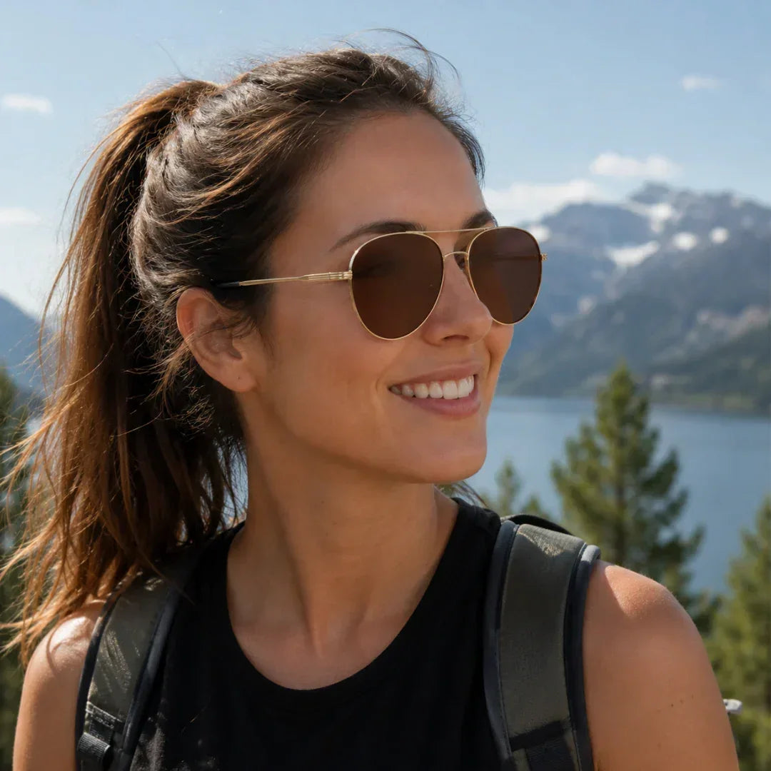 Woman wearing stylish polarized sunglasses with UV protection, enjoying mountain lake view